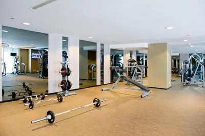 a gym with several treadmills and machines in it at The Stones Hotel - Legian Bali in Kuta