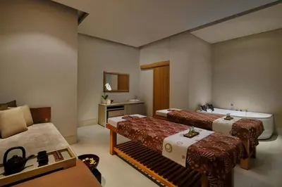 a room with two beds and a tub and a sink at The Stones Hotel - Legian Bali in Kuta