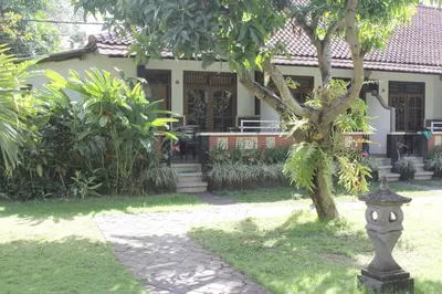 a house with a tree in front of a yard at Mangga Bali Inn in Legian