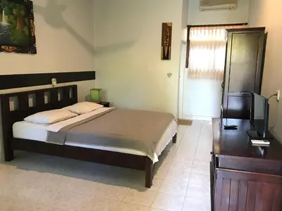 a bedroom with a bed and a flat screen tv at Mangga Bali Inn in Legian