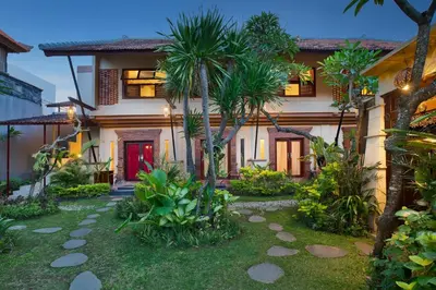 a house with a red door and palm trees at Mahe Garden Kuta Villas by Kamara in Kuta