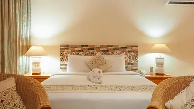 a stuffed animal sitting on a bed with two chairs at AlamKulkul Boutique Resort in Kuta