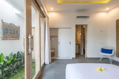 a bedroom with a white bed and a blue chair at Villa Arif in Seminyak