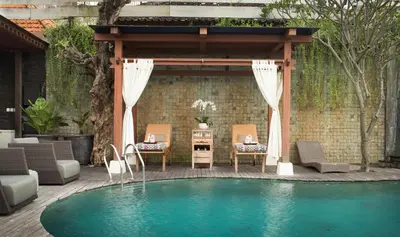 a swimming pool with chairs and a gazebo at Daluman Villas in Seminyak