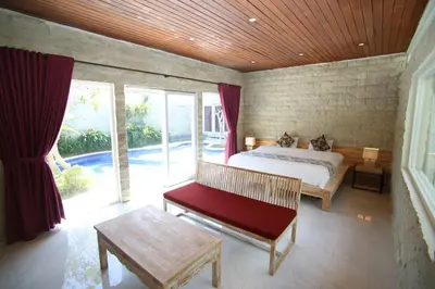 a bedroom with a bed and a bench and windows at Villa Latour in Seminyak