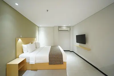 a hotel room with a bed and a flat screen tv at Episode Kuta Bali in Kuta