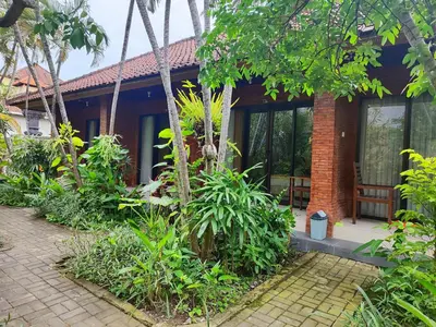a house in the middle of a garden at Adus Beach Inn in Legian