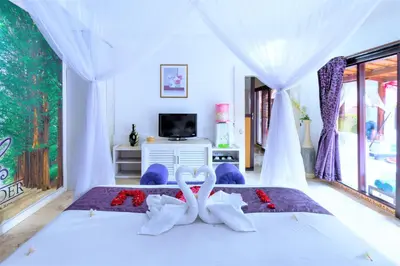 two white swans sitting on a bed in a bedroom at Lavender Villa & Spa in Kuta