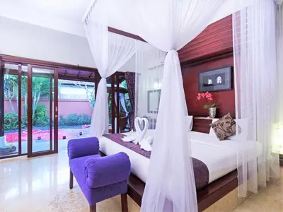 a bedroom with a canopy bed and a purple chair at Lavender Villa & Spa in Kuta
