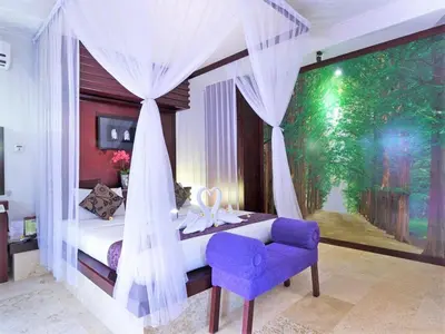 a bedroom with a canopy bed with a purple chair at Lavender Villa & Spa in Kuta
