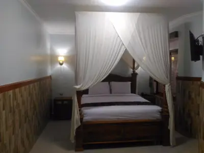 a bedroom with a canopy bed with white curtains at Hotel Sorga Cottages in Kuta