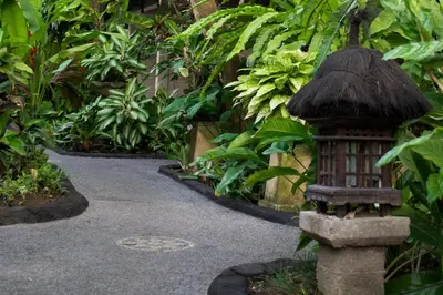 a garden with a bird bath in the middle of a walkway at Flamboyan Hotel in Kuta