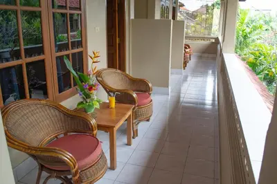 a porch with wicker chairs and a wooden table at Flamboyan Hotel in Kuta