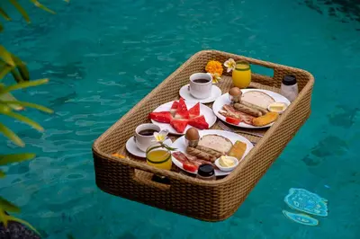 a tray of breakfast food on a table in a swimming pool at Villa Verde in Seminyak