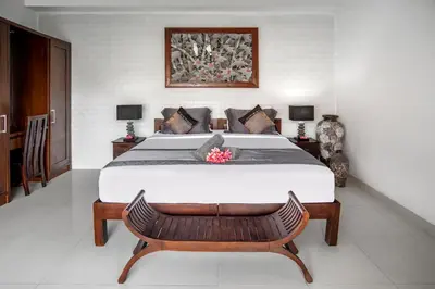 a bedroom with a large bed with a wooden bench at Villa Verde in Seminyak