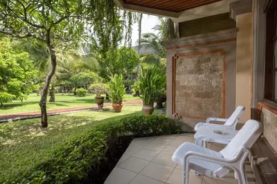 a patio with two white chairs and a garden at The Jayakarta Bali Beach Resort in Legian