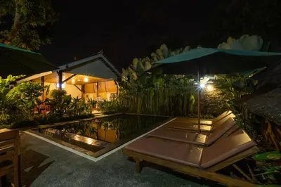 a pool with an umbrella next to a house at Kubu Kak Dudung Villas in Jimbaran