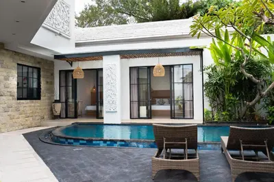 a villa with a swimming pool and two chairs at Awila Villas Kuta by The Wina Resorts in Legian