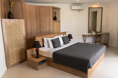 a bedroom with a bed and a table with a chair at Awila Villas Kuta by The Wina Resorts in Legian