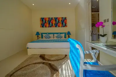 a bedroom with a bed with a blue blanket on it at Awila Villas Kuta by The Wina Resorts in Legian