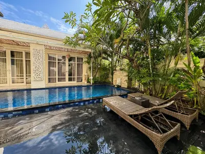 a swimming pool with a table and chairs next to a house at Awila Villas Kuta by The Wina Resorts in Legian