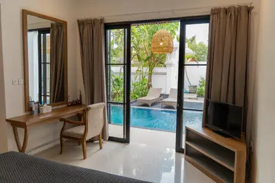 a bedroom with a desk and a tv and a mirror at Awila Villas Kuta by The Wina Resorts in Legian