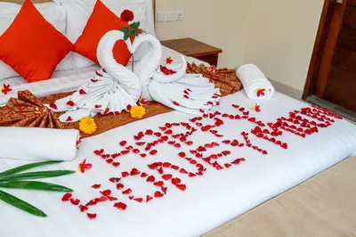 a bed with a bunch of red flowers on it at De' Bharata Bali Villas in Seminyak