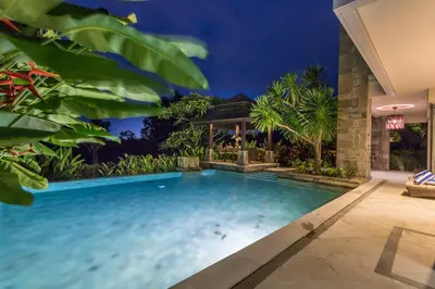 a swimming pool in front of a house with trees at Villa Deh Simba at Ayana With Private Pool in Jimbaran