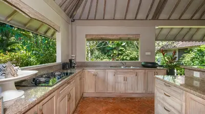a kitchen with wooden cabinets and a sink and two windows at Villa Koyama by Villa Finder in Seminyak