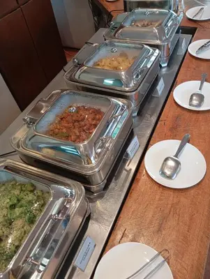 a buffet with several trays of food on a table at Kuta Town House Apartments in Kuta