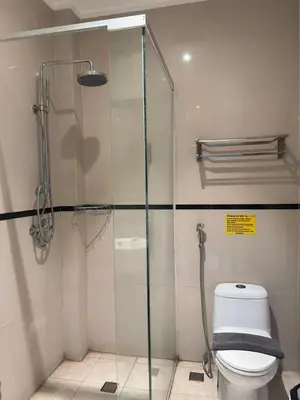 a bathroom with a glass shower with a toilet at Kuta Town House Apartments in Kuta