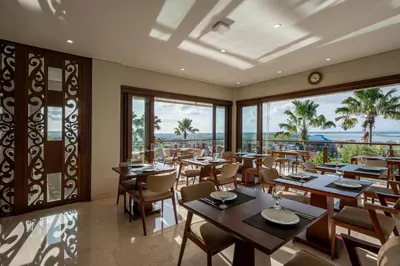 a restaurant with tables and chairs and a view of the ocean at tanadewa Villas Nusa Dua Bali by Cross Collection in Nusa Dua
