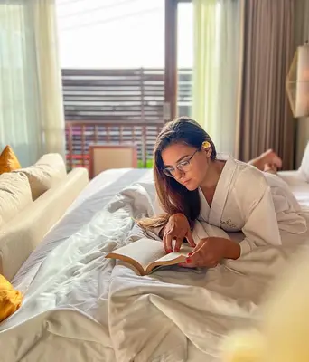 a woman laying in bed reading a book at tanadewa Villas Nusa Dua Bali by Cross Collection in Nusa Dua