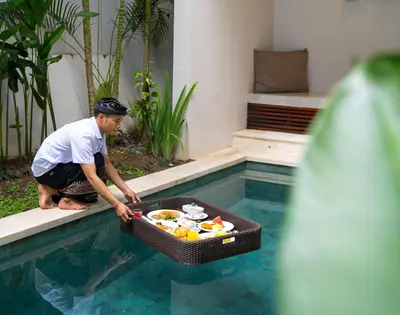 a man with a basket of food in a swimming pool at tanadewa Villas Nusa Dua Bali by Cross Collection in Nusa Dua