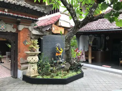 a garden in front of a building with a statue at De Puspa Residence Seminyak in Seminyak