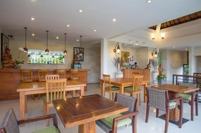 a restaurant with wooden tables and chairs and a bar at Sandi Agung Villa in Seminyak