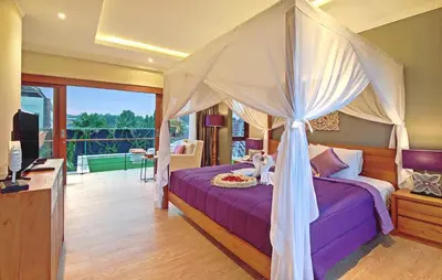 a bedroom with a canopy bed and a balcony at Kubu GWK Resort in Jimbaran