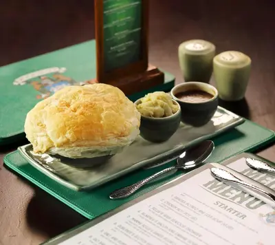 a plate of food with a sandwich and dipping sauce at Bali Dynasty Resort in Kuta