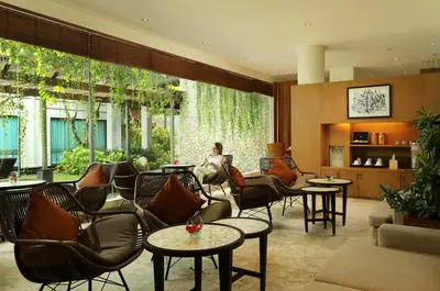 a lobby with chairs and tables and a person in a room at Padma Resort Legian in Legian