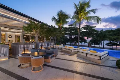 a patio with couches and tables and a pool at Padma Resort Legian in Legian