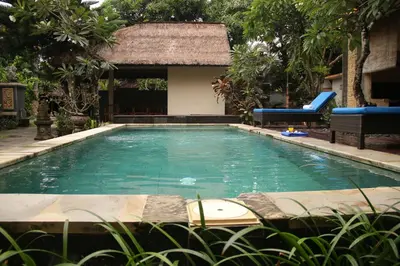 a swimming pool with a slide in a garden at Eddys Cottages & Villa in Legian
