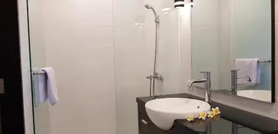 a white bathroom with a sink and a mirror at Eddys Cottages & Villa in Legian