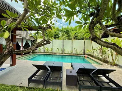 a swimming pool with a table and chairs next to a house at Nil Villa Seminyak in Seminyak