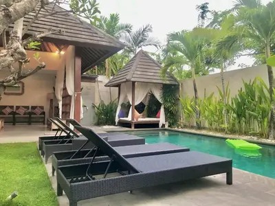 a pool with lounge chairs and a gazebo at Nil Villa Seminyak in Seminyak