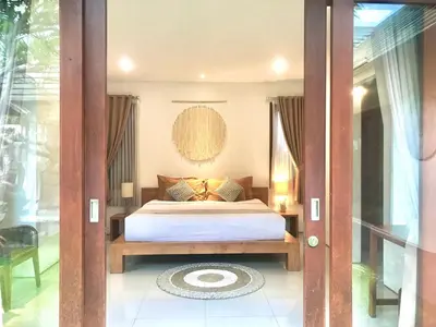 a bedroom with a bed and a glass door at Nil Villa Seminyak in Seminyak