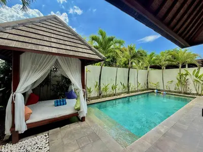 a bed in a gazebo next to a swimming pool at Nil Villa Seminyak in Seminyak