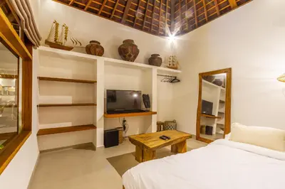 a bedroom with a bed and a tv and a table at Villa Namu by Alfred in Bali in Seminyak
