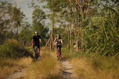 two people riding bikes down a dirt road at The Kayana in Seminyak