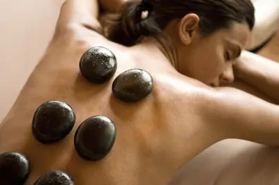 a woman laying on her back with rocks on her back at The Samaya Seminyak Bali in Seminyak