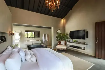 a bedroom with a large white bed and a tv at Villa Suku Berawa in Canggu
